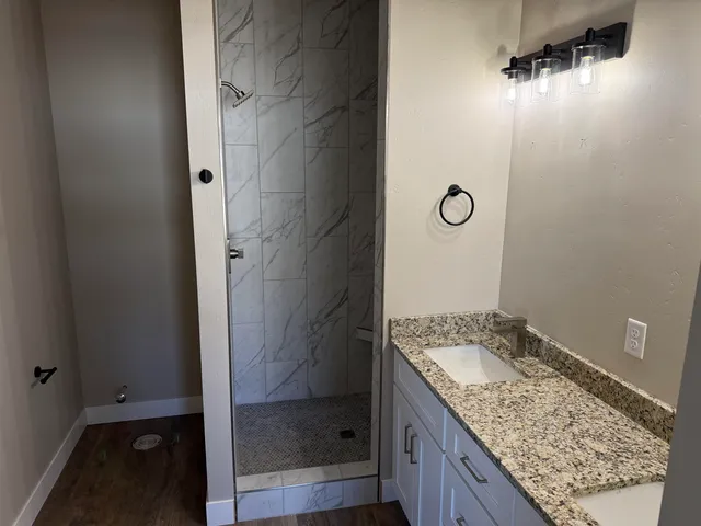 a bathroom with a granite countertop sink a mirror and shower