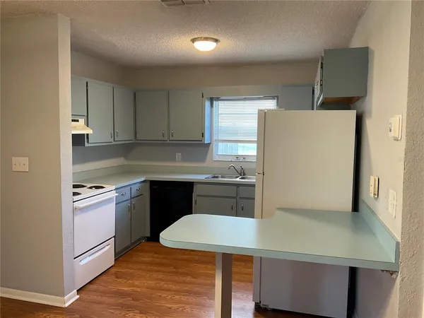 a kitchen with stainless steel appliances a refrigerator a sink and white cabinets