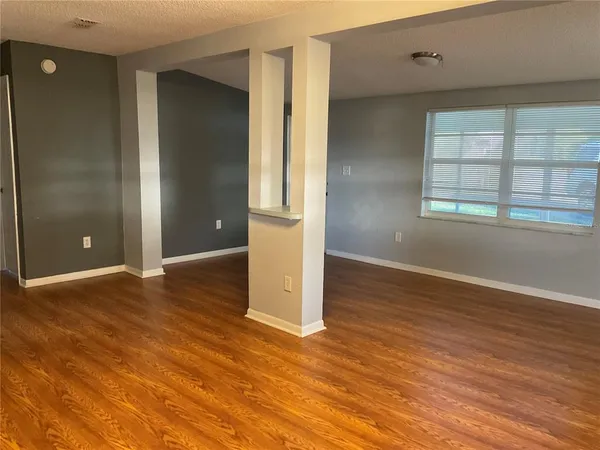 an empty room with wooden floor and windows