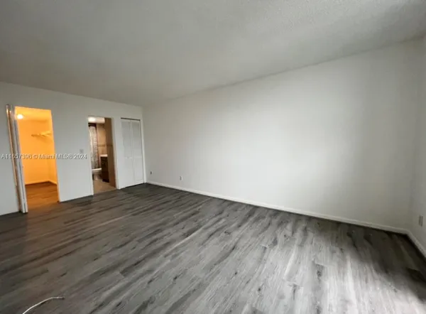 a view of an empty room and wooden floor and a window