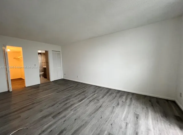 a view of an empty room and wooden floor and a window