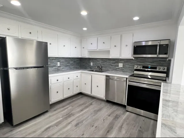 a kitchen with cabinets stainless steel appliances and wooden floor
