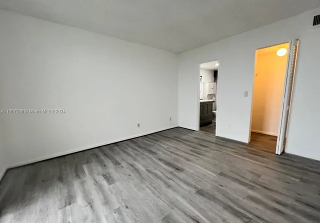 a view of empty room with wooden floor and entryway