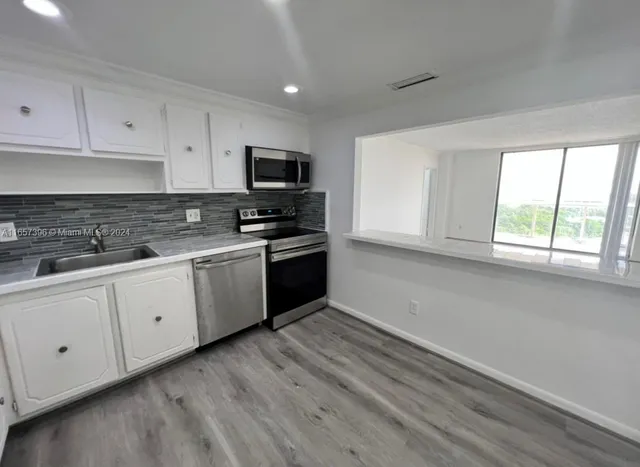 a kitchen with white cabinets stainless steel appliances and window