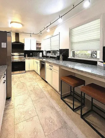 a kitchen with stainless steel appliances granite countertop a stove a sink and a microwave