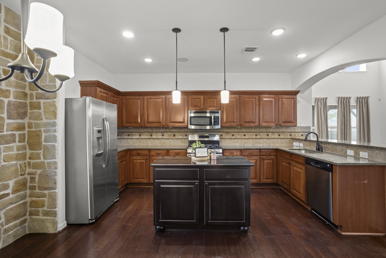 245 Razzmatazz Trail Buda, TX 78610 - Photo 11 of 37 Spacious kitchen featuring rich wood cabinetry, granite countertops, and stainless steel appliances