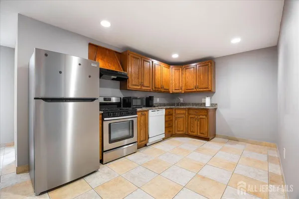 a kitchen with stainless steel appliances granite countertop a refrigerator a sink dishwasher a stove with wooden cabinets and a refrigerator