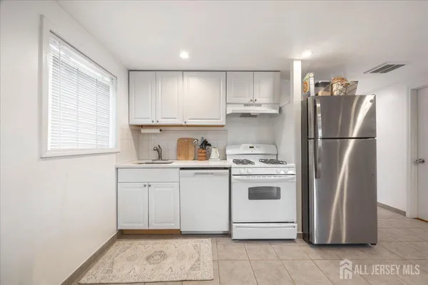 a kitchen with a white stove refrigerator and white cabinets with wooden floor