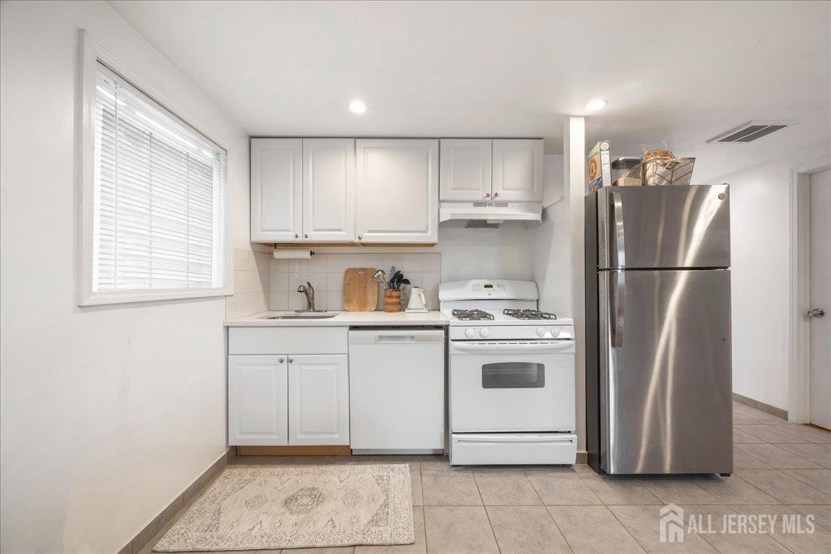 281 Prospect Avenue Old Bridge, NJ 08879 - Photo 21 of 29 a kitchen with a white stove refrigerator and white cabinets with wooden floor