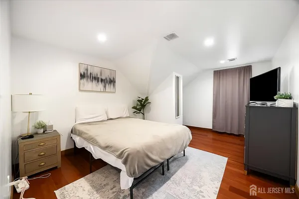 a bedroom with a bed and a flat tv screen on dresser