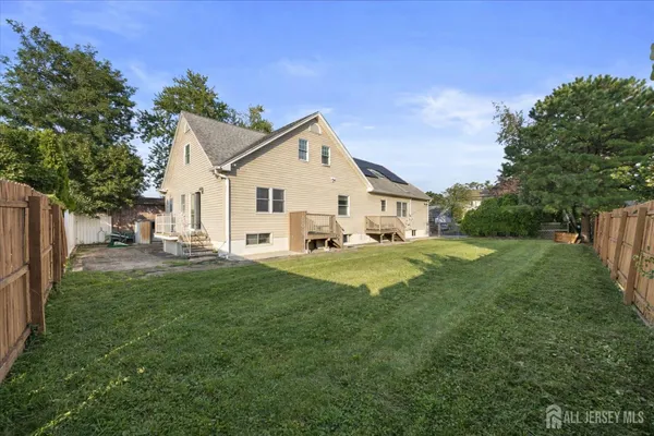 a view of a white house that has a small yard and large trees