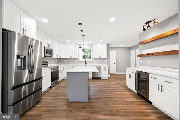 a large kitchen with stainless steel appliances kitchen island a large counter top and a stove top oven