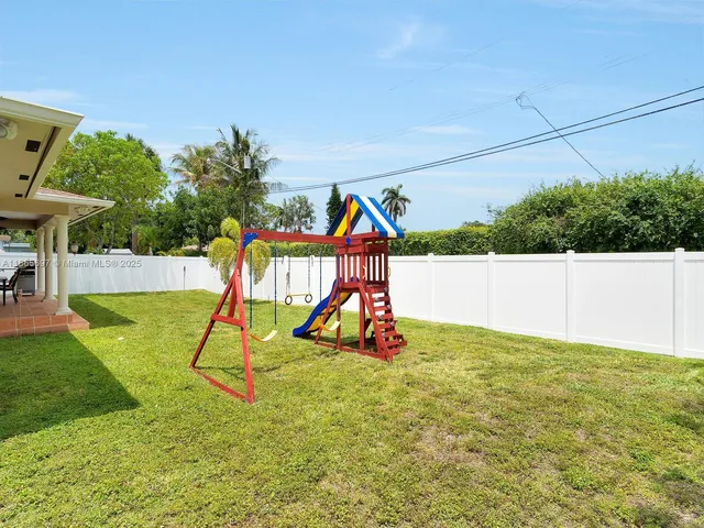 a view of a backyard with a slide and potted plants