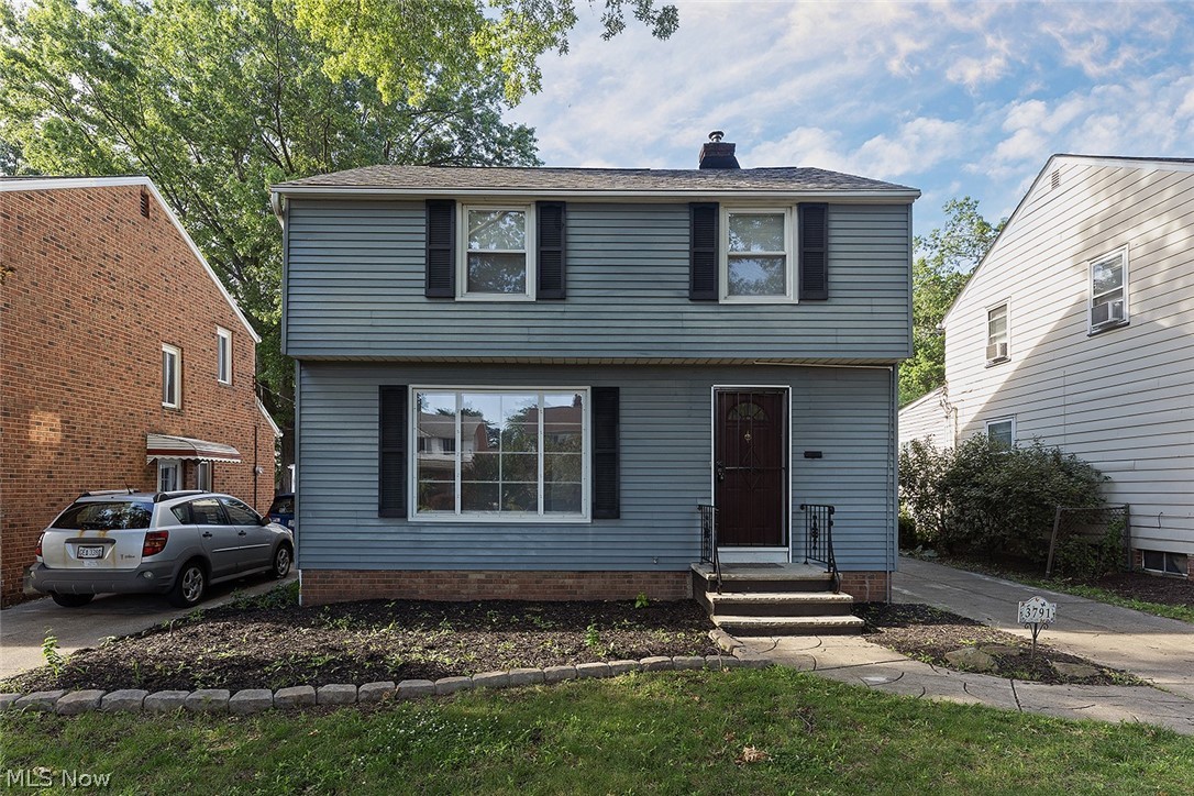 3791 Fairoaks Road South Euclid, OH 44121 - Photo 2 of 30 Two-story residence featuring light blue siding with black shutters, a dark entryway door with a storm door, and a concrete pathway leading to the entrance