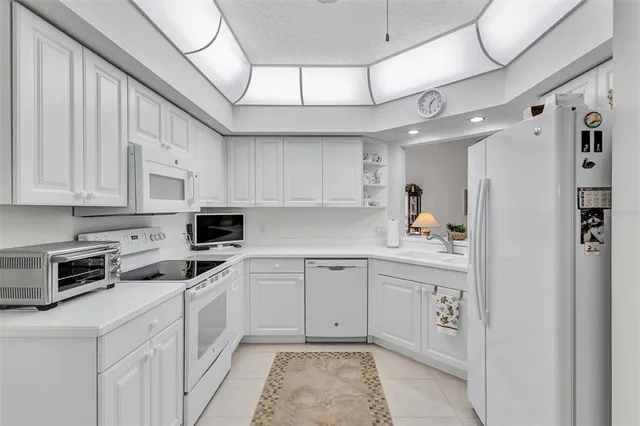 a kitchen with granite countertop white cabinets and white appliances