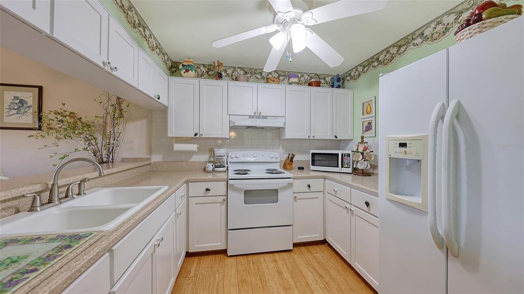 1196 Bird Bay Way, Unit 310 Venice, FL 34285 - Photo 4 of 37 a kitchen with a sink a refrigerator a stove and cabinets