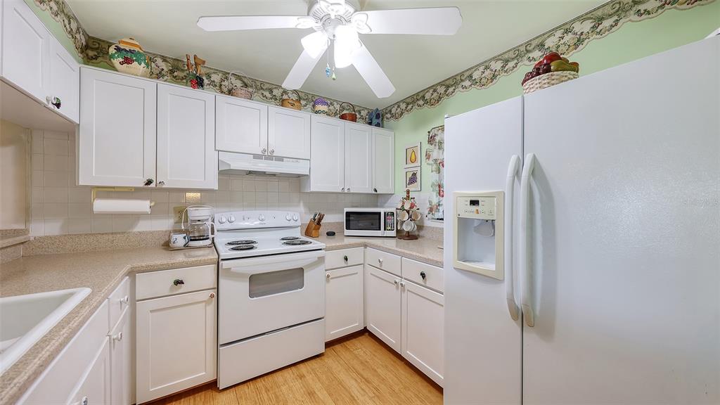 1196 Bird Bay Way, Unit 310 Venice, FL 34285 - Photo 5 of 37 a kitchen with white cabinets and white appliances