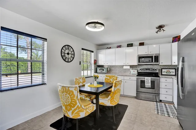 a kitchen with stainless steel appliances granite countertop a stove a refrigerator a microwave oven with a dining table and chairs with wooden floor