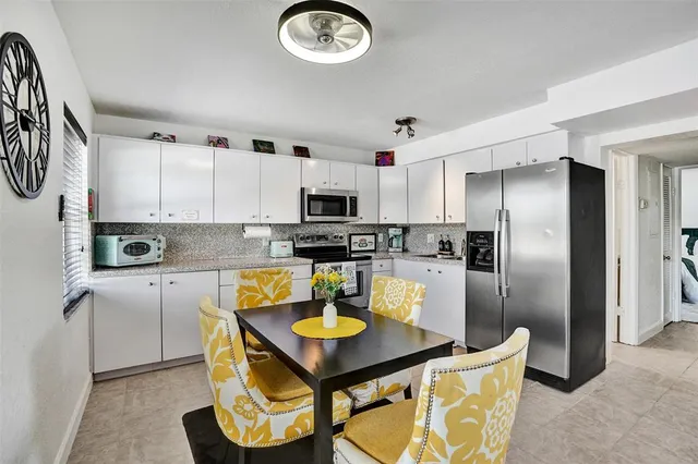 a kitchen with stainless steel appliances granite countertop a sink a stove a refrigerator cabinets and chairs