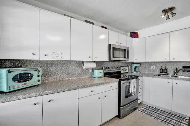 a kitchen with granite countertop white cabinets and white appliances