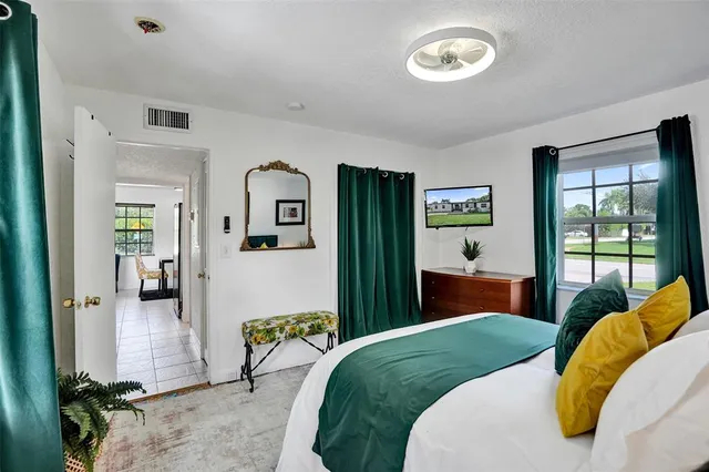 a bedroom with a bed mirror and a window