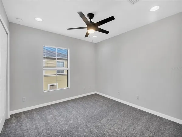 an empty room with ceiling fan and window