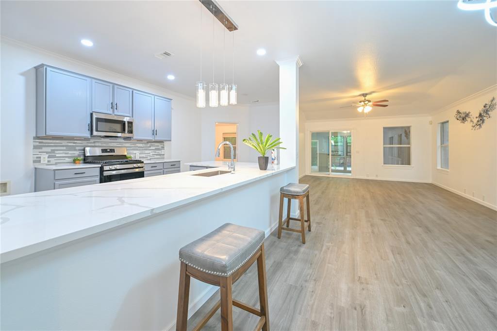 910 Rocking Spur Cove Pflugerville, TX 78660 - Photo 17 of 17 An open concept floorplan features a modern kitchen with a large island and ample counter space, flowing into a spacious living area.