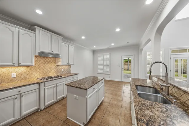 a kitchen with granite countertop sink stainless steel appliances and white cabinets