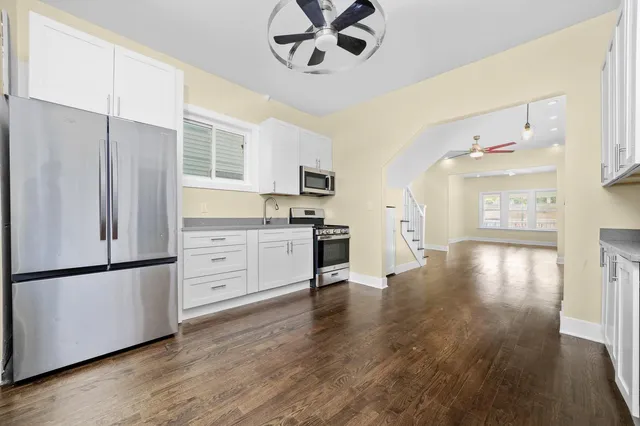 a kitchen with stainless steel appliances granite countertop a refrigerator a stove and a microwave with wooden floor