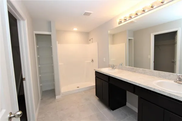 a bathroom with a double vanity sink mirror and shower
