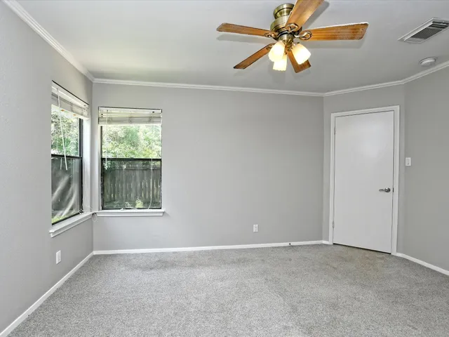 an empty room with windows and fan
