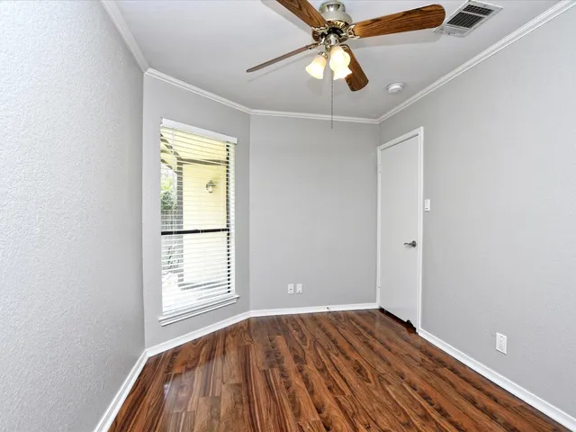 an empty room with wooden floor fan and windows