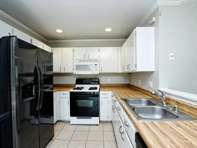 a kitchen with stainless steel appliances granite countertop a sink stove refrigerator and cabinets