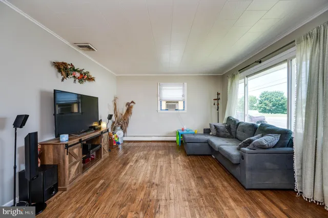 a living room with furniture a flat screen tv and a floor to ceiling window