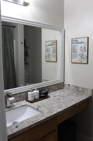 a bathroom with a granite countertop sink and a mirror