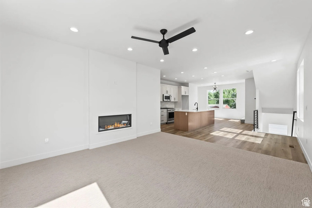 545 East 7215 South Midvale, UT 84047 - Photo 10 of 27 Unfurnished living room with ceiling fan, a glass covered fireplace, suspended lighting, and dark carpet