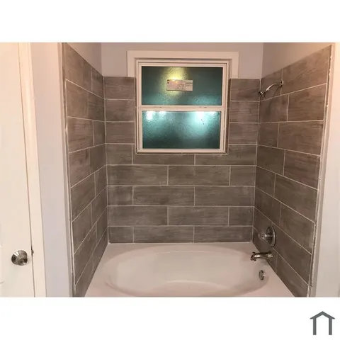 a bathroom with a tub shower and a toilet
