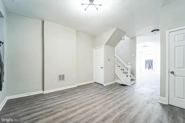 a view of an empty room with wooden floor and a ceiling fan