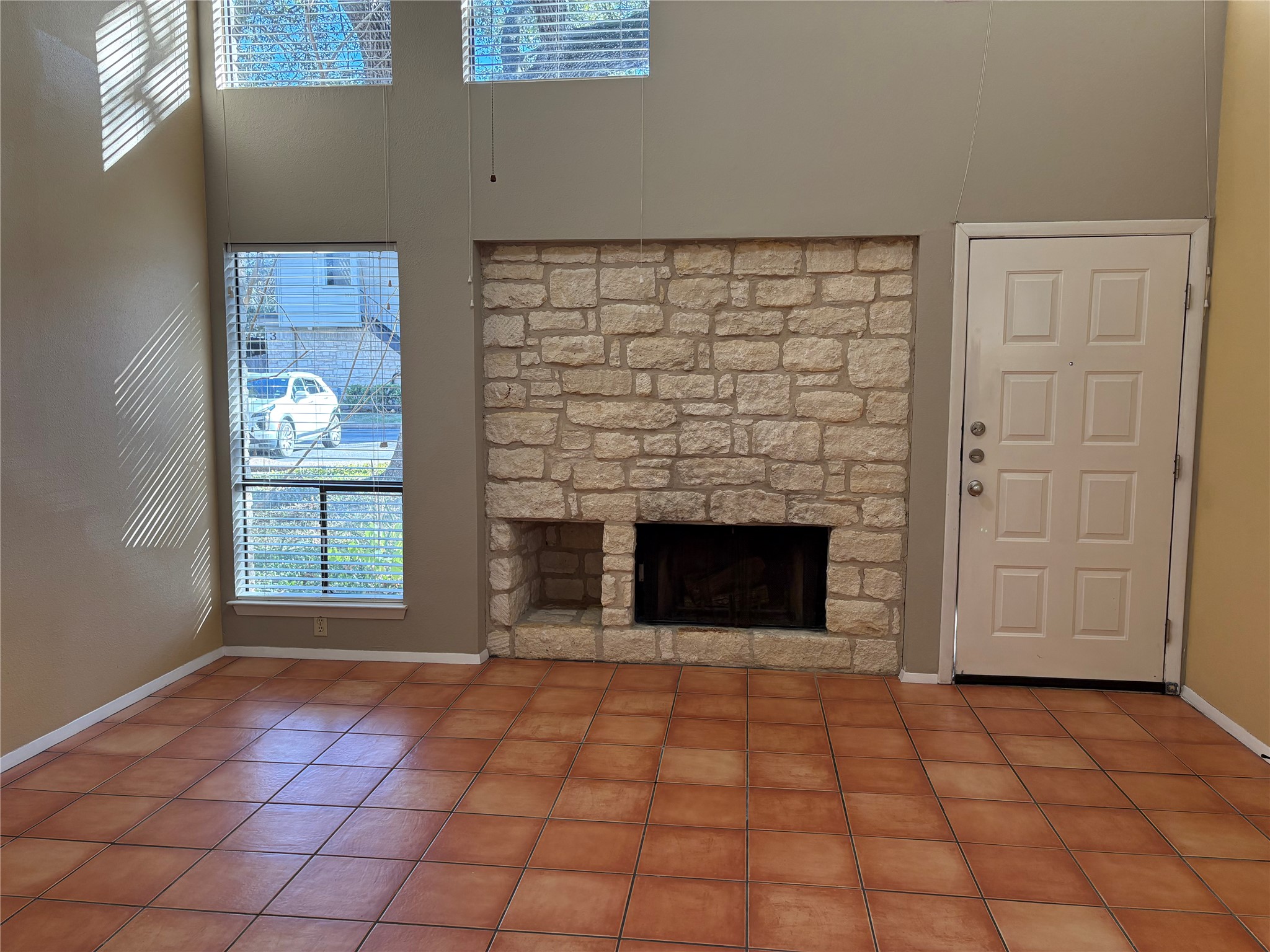 9226 Jollyville Road, Unit 144 Austin, TX 78759 - Photo 3 of 40 Unfurnished living room featuring a stone fireplace, a towering ceiling, tile patterned floors, and healthy amount of natural light
