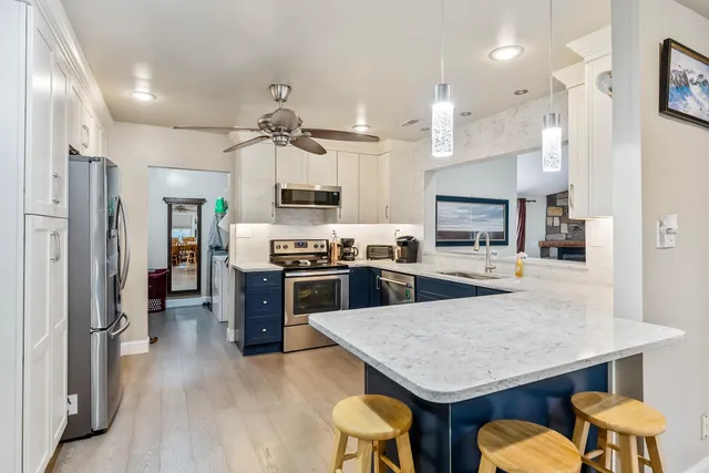 a kitchen with stainless steel appliances granite countertop a kitchen island a stove a refrigerator a sink a dining table and chairs