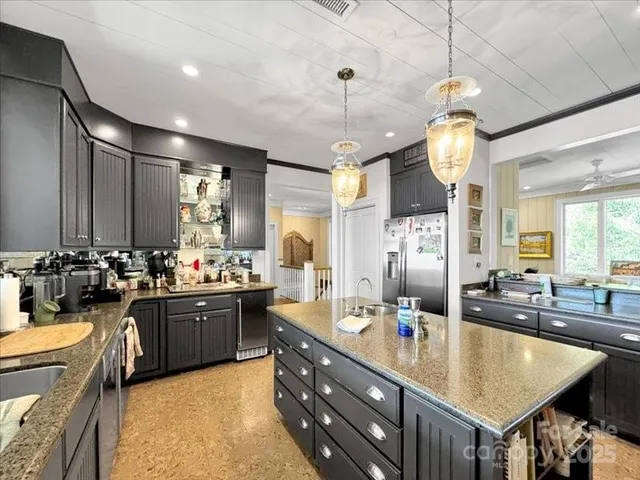 a large kitchen with kitchen island a large counter top space a sink stainless steel appliances and cabinets