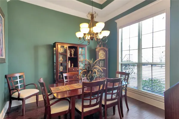 a view of a dining room with furniture a chandelier and large windows