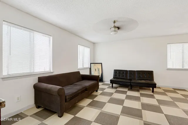 a living room with a black white checkered floor with a gaming machine and a rug