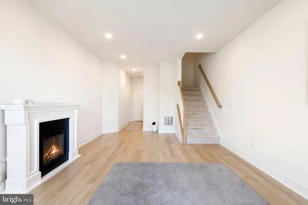 a view of a living room with wooden floor and a fireplace