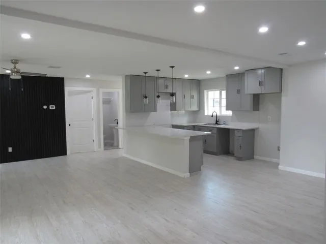 a kitchen with stainless steel appliances kitchen island granite countertop a refrigerator a sink a stove and white cabinets