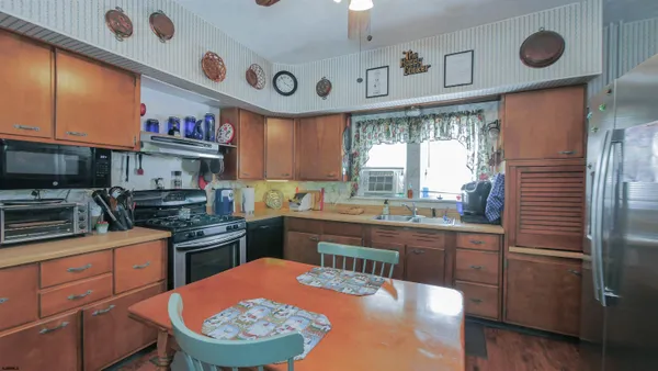 a kitchen with stainless steel appliances a sink a stove a refrigerator cabinets and a window