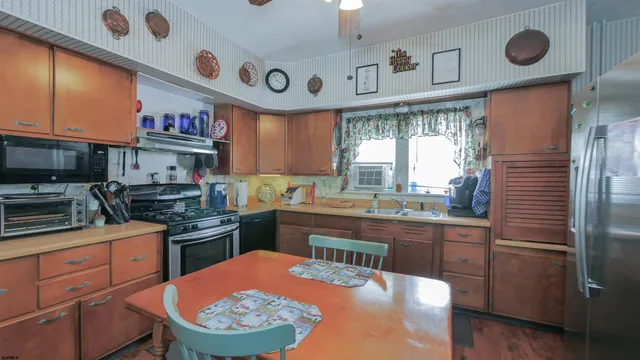 a kitchen with stainless steel appliances a sink a stove a refrigerator cabinets and a window