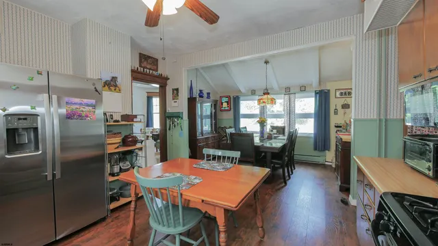 a kitchen with stainless steel appliances granite countertop a dining table chairs refrigerator sink and cabinets