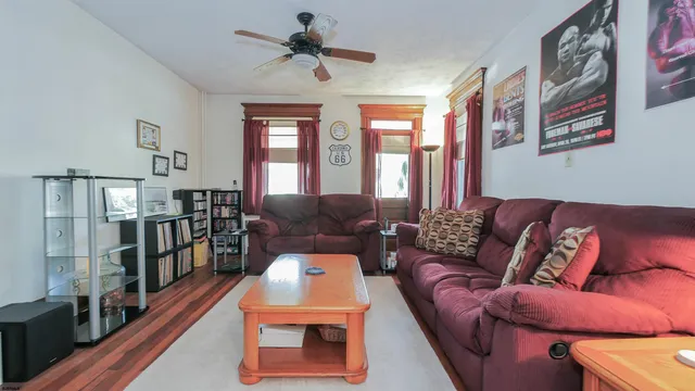 a living room with furniture a ceiling fan and a book shelf