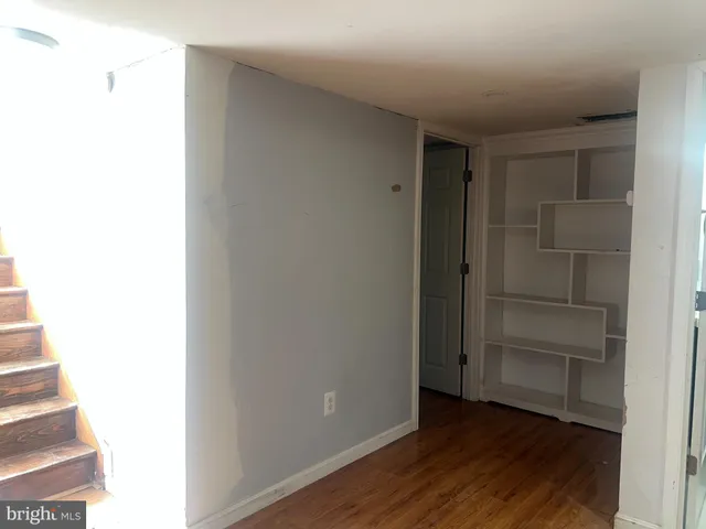 a view of an empty room with wooden floor and closet